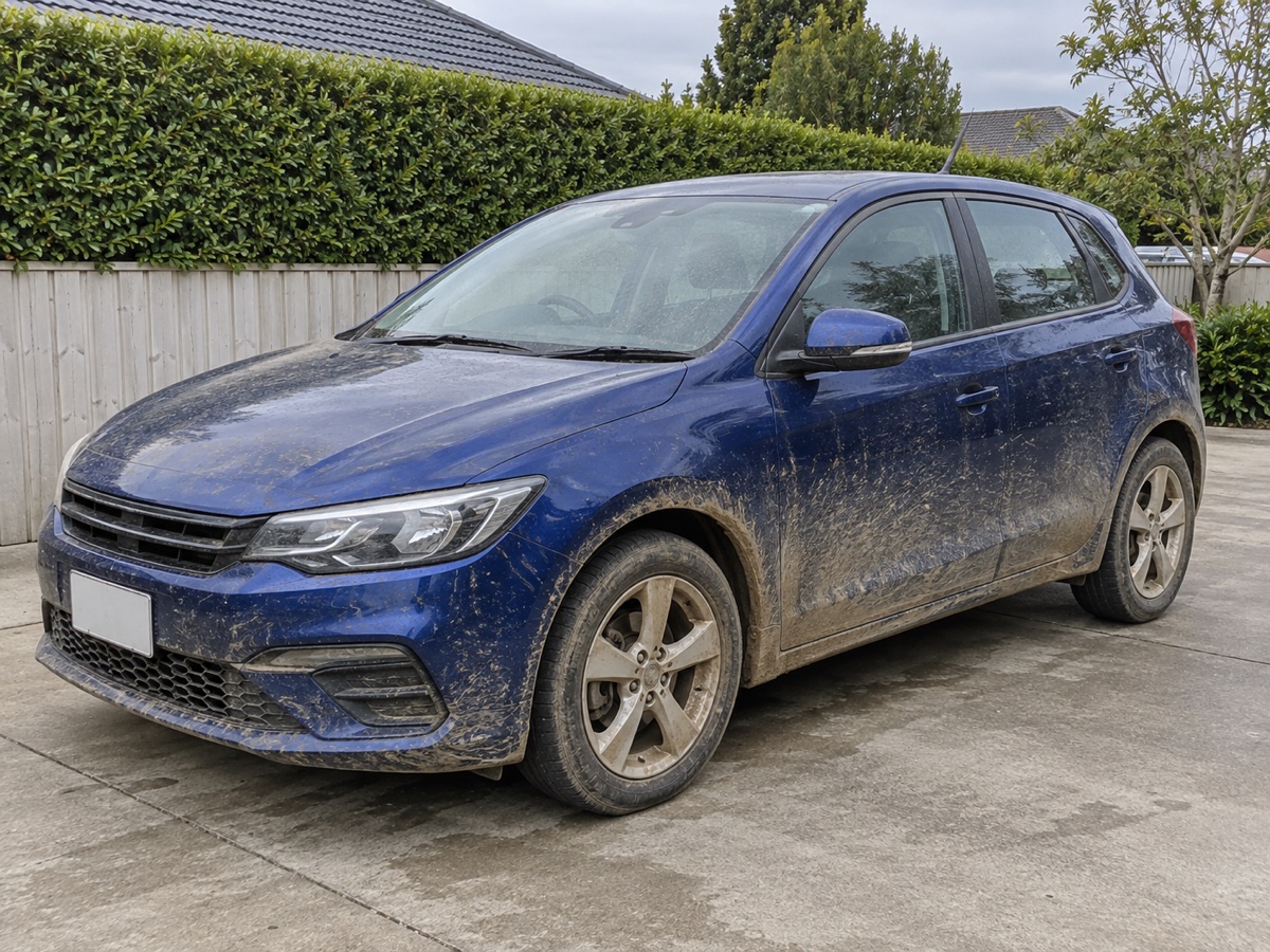 Blue hatchback before detailing, with mud on the body and wheels
